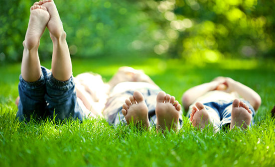 Group of happy children lying on green grass outdoors in spring park